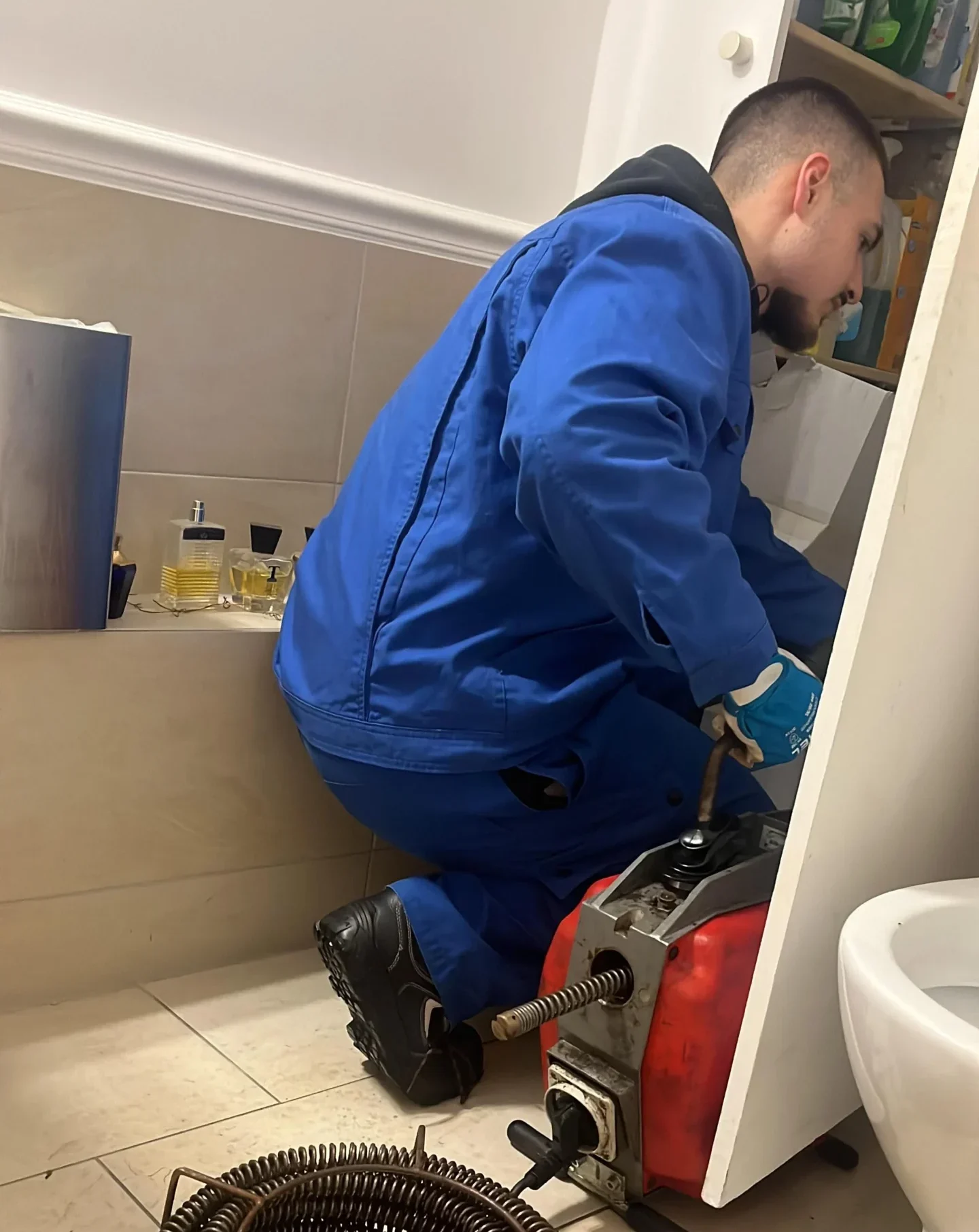 Monteur setzt eine Rohrreinigungsmaschine im Badezimmer ein