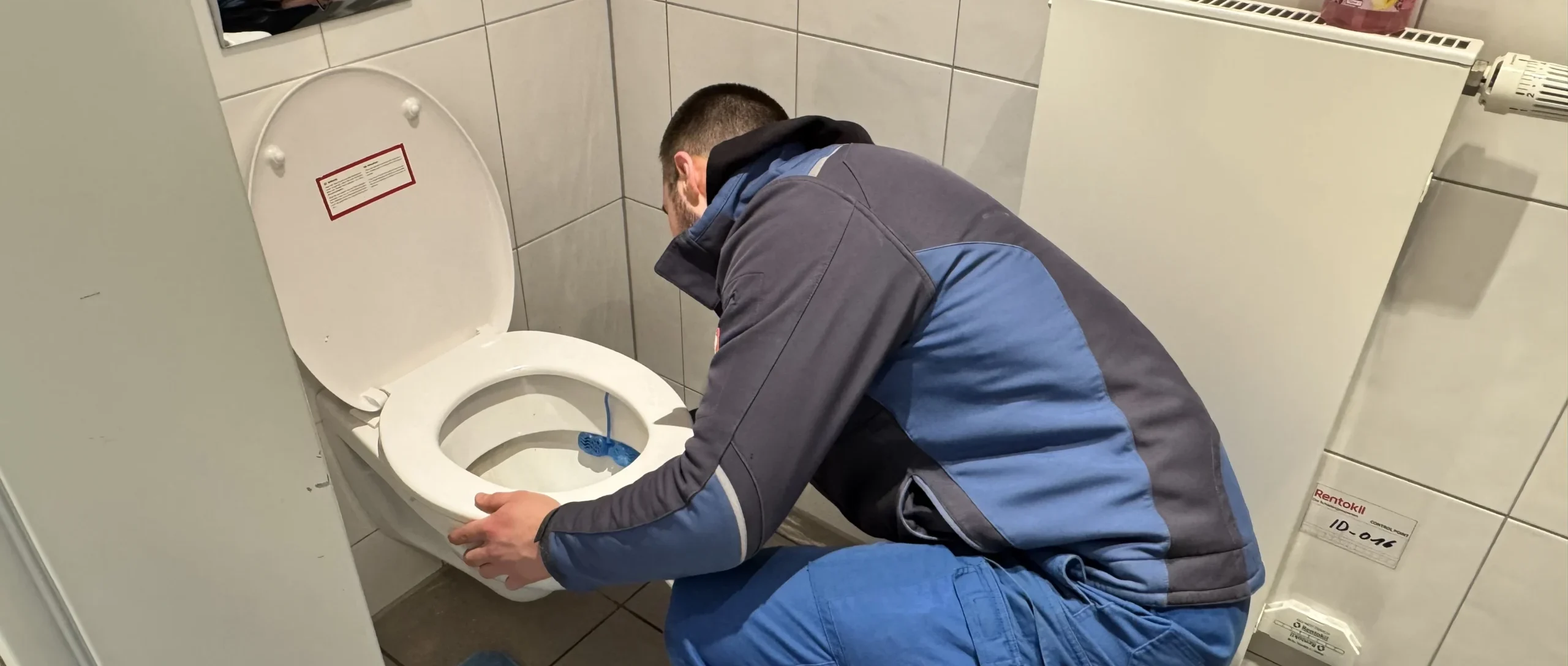 Monteur beseitigt eine WC-Verstopfung im Badezimmer